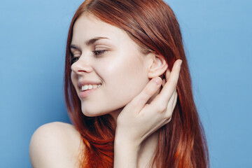 Fototapeta premium attractive woman with bare shoulders red hair close-up blue background