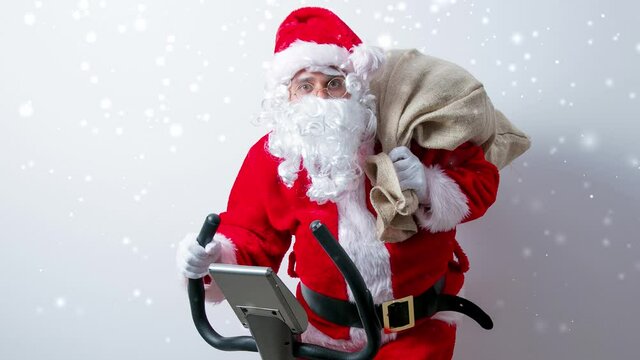 Funny Santa Claus have a fun with Exercise Bikes on white background