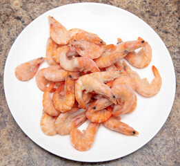 Red frozen shrimps on a white plate.