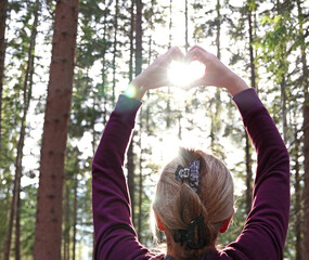 Female hands in the form of heart with the sunlight passing through the hands in the forest. Hands in shape of love heart, Love concept