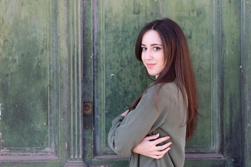 Fototapeta premium Young Brunette stylish lady posing in a green old door background
