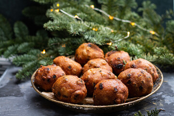 Oliebollen traditional Dutch New Year's Eve pastry dusted with powder sugar served with champagne. New year lights bokeh and sparkles on background.

