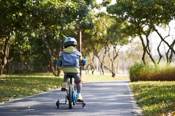 Foto op Plexiglas rear view of asian little girl riding bike outdoos in park © imtmphoto