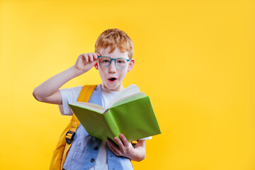 Surprised teenager boy reading book on yellow background © lithiumphoto