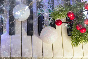 flat lay of piano with white christmas balls and branch of christmas tree on bokeh background. New Year or Christmas music concept.
