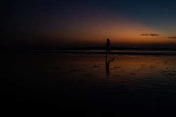 beautiful girl runs along the beach at sunset
