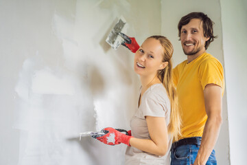 A man and a woman are plastering the walls of the house. DIY home renovation