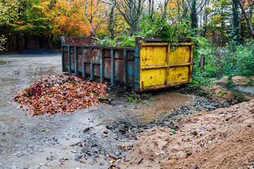 Big size metal skip in a park for fallen leaf and rubbish removal. Heavy industrial container to...