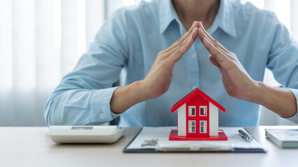 The real estate concept the realtor presenting his work towards his customer by putting the red house model in front of him, raising his hands and putting his hand together