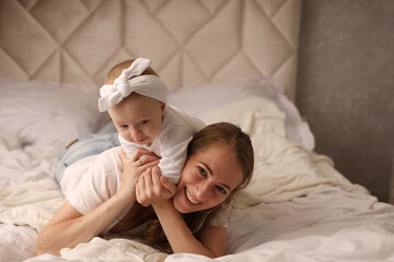 Obraz na płótnie Canvas Mom hugs a cute blonde baby on a white bed. motherhood. breastfeeding. High-quality photography