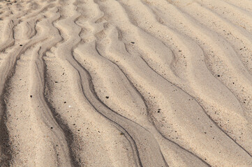 natural sand pattern created by a flow of tide and ripples on the edge of a beach