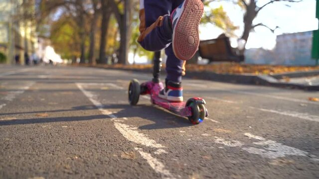 cheerful young little boy rides on roller ,scooter in the city in autumn sunny weather