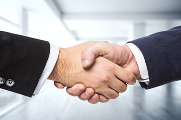 Two businessmen shake hands on the background of empty modern office, signing of a contract...