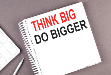 THINK BIG DO BIGGER text on the notebook with calculator and pen