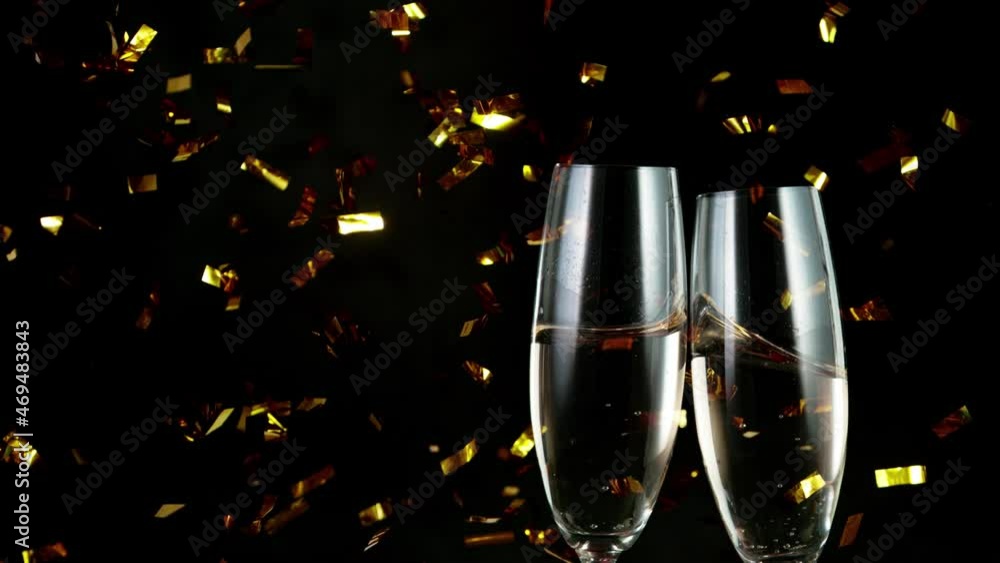 Wall mural super slow motion of having a toast with two champagne glasses. glittering confetti. isolated on bla