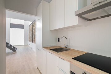 New kitchen with oven, stove and extractor. Interior with white cabinets and wooden counter top.