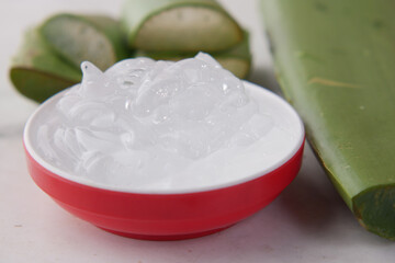 Fresh aloe vera sliced and liquid gel in plastic container on white background 