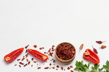 Dry paprika petals in bowl, halves of red peppers, and dry pepper pods.