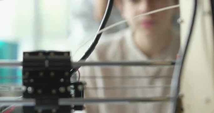 Young students looking at the 3D printer printing a prototype