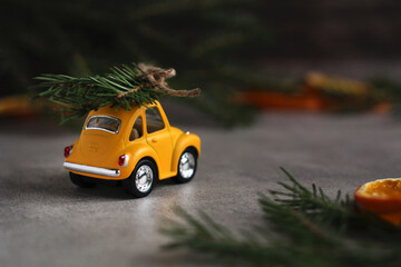 yellow retro car with spruce branches on a gray background