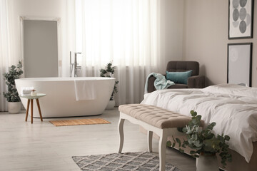 Obraz premium Stylish light apartment interior with white bathtub and bed
