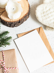 Winter composition of knitted mittens, envelope and paper card, candles and present on white background.