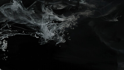 White and black watercolor ink mixed in water on a black background. Relaxing meditative background. Milky white and black awesome abstract background.