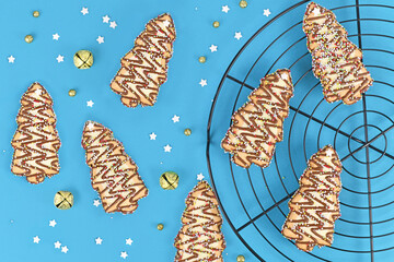 Christmas tree shaped cookies with sugar sprinkles on blue background