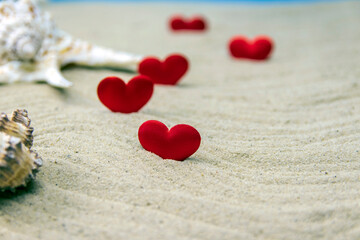 Fototapeta na wymiar Seashells on the sand with red hearts, selective focus on the heart.