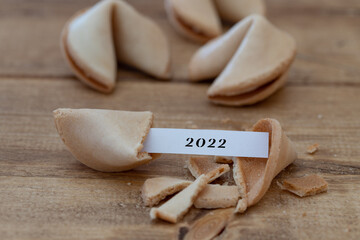 close-up of a broken fortune cookie with a paper strip and 2022 on it, focus on foreground