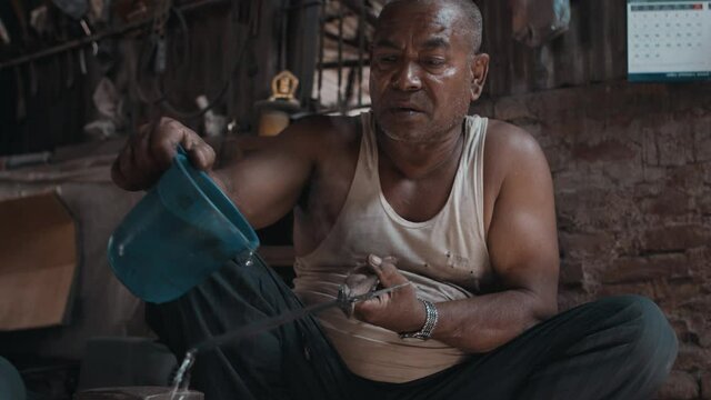 Blacksmith pours water on hot knife to cool it down