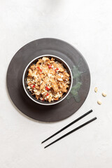 Bowl with chicken fillet and rice in sauce in a black bowl. Flatlay, vertical