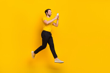 Fototapeta na wymiar Full size profile side photo of young addicted guy chat type cellphone 4g post like walk jump isolated over yellow color background