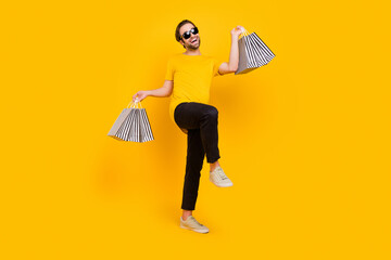 Full length photo of young excited man good mood hold shopping bag store go walk isolated over...