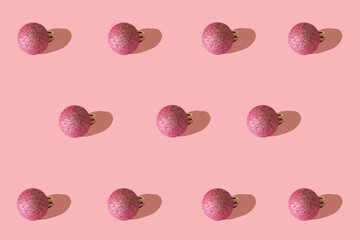 Christmas creative pattern made of sparkle peony colour baubles on pastel pink background. Winter holidays and New Year ornaments idea.