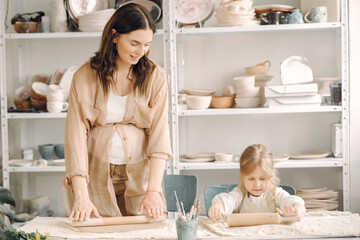Portrait of mother and little girl shaping clay together