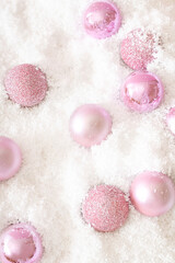 Christmas sparkle pink baubles in white snow pattern. Winter holidays and New Year aesthetic layout. Christmas ornaments composition.
