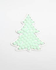 Christmas tree shape frame filled with snow sparkle green neon colour balls ornaments against white background. Minimal winter holidays and New Year concept.