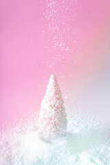 Christmas pink tree with falling snow with pink and icy blue light. Winter holidays and New Year idea. Vaporwave 80s and 90s aesthetic.