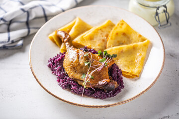 Portion of duck leg with red cabbage and potato pancakes, a traditional autumn dish in Eastern Europe