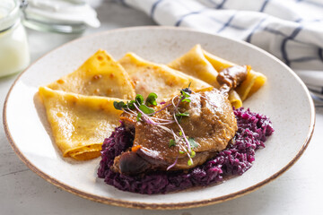 Portion of duck leg with red cabbage and potato pancakes, a traditional autumn dish in Eastern Europe