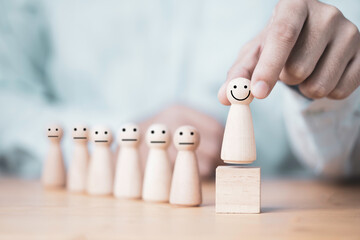Hand holding smiley wooden model figure on wooden cube block , promotion to leadership and management growth concept.