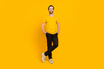 Fototapeta na wymiar Full body photo of cheerful young guy standing arms in pocket good mood isolated over yellow color background