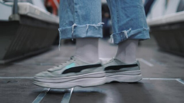 Close up female feet in sneakers standing in metro, bus or any transport and then going out away 