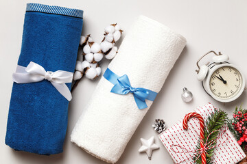 White and blue terry towels with a bow on a light gray background. Branch of cotton gift alarm...