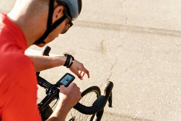 Young white cyclist using gadget while working out on city road