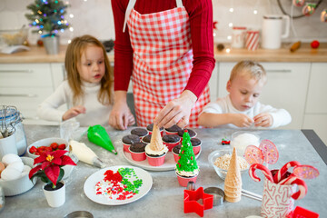 Brother and sister making cupcakes with their mom