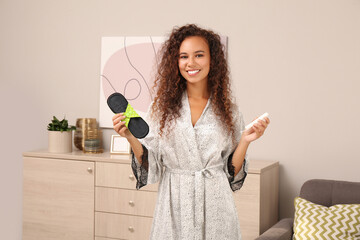 Young African American woman with reusable menstrual pad and tampon at home