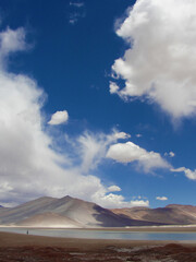 Fototapeta na wymiar Desert landscape showing mountains and lake, with attention directed to a deep blue sky with white, fluffy clouds. Piedras Rojas, Atacama Desert, Chile. January, 2015.