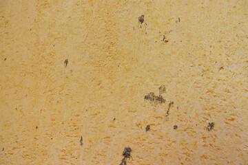 Old, yellow textured wall stained with cement spots, for background use.